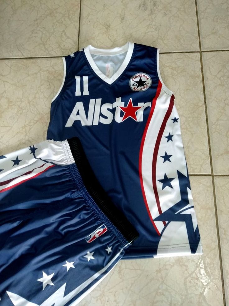 A navy blue basketball jersey and matching shorts set with a patriotic red, white, and blue star-and-stripe design, laid flat on a beige tiled floor. The jersey features 'Allstar' and a circular star logo on the chest.