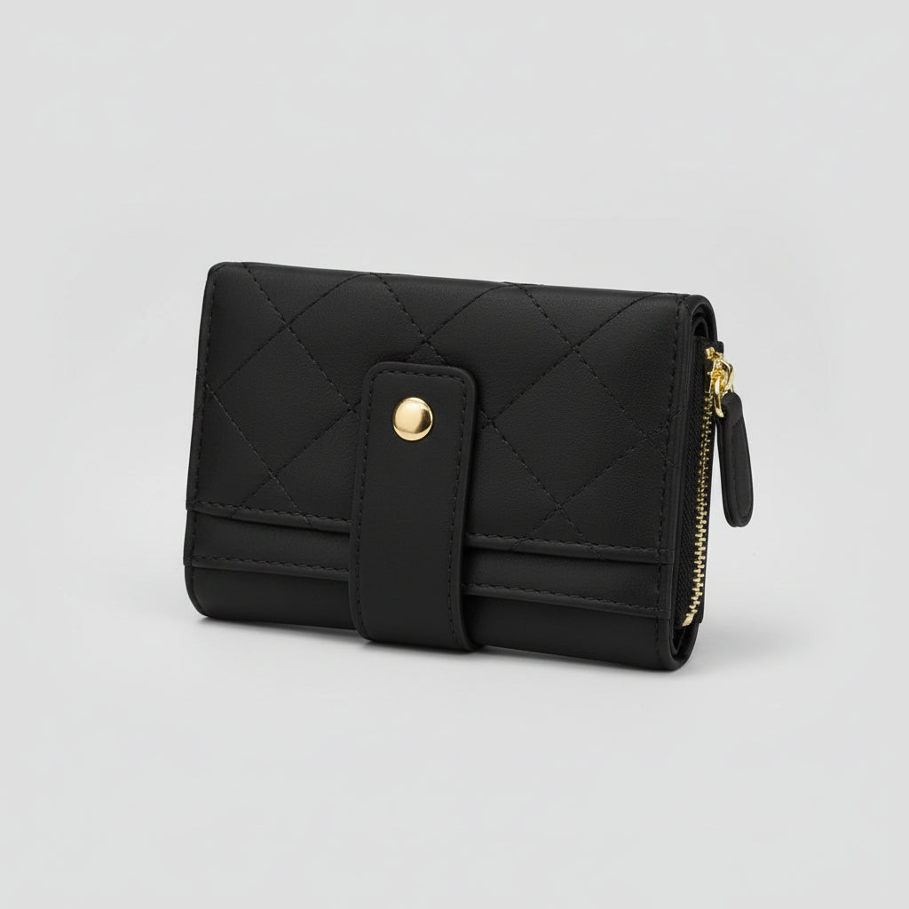 Black quilted faux-leather bifold wallet with a gold snap button and gold zipper, displayed on draped mauve satin fabric over a tan background.