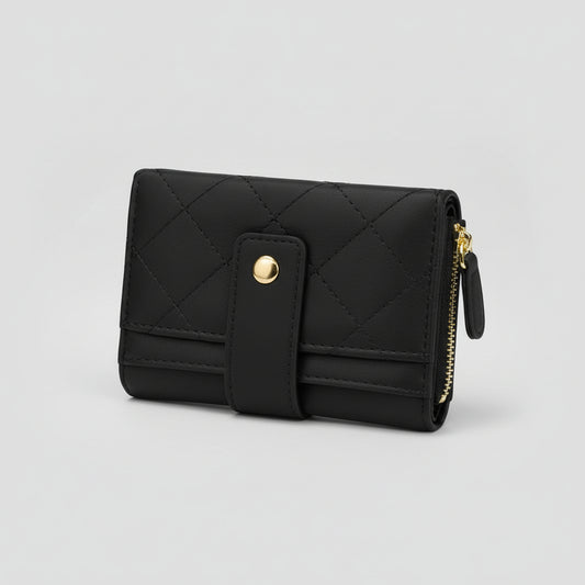Black quilted faux-leather bifold wallet with a gold snap button and gold zipper, displayed on draped mauve satin fabric over a tan background.