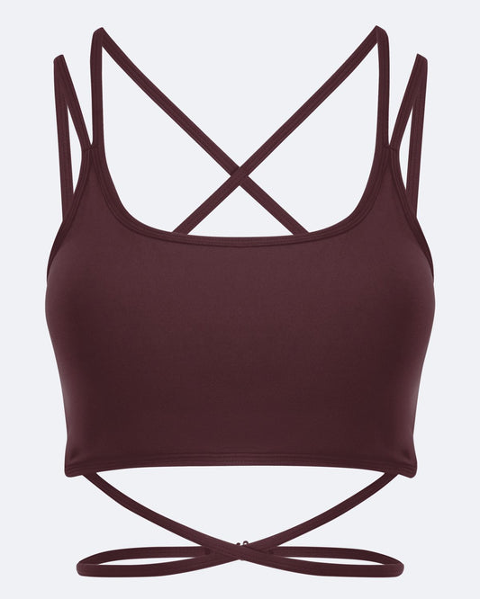 A dark burgundy sports bra with thin crisscrossing shoulder straps and a matching tie detail at the underbust, shown against a light gray background.