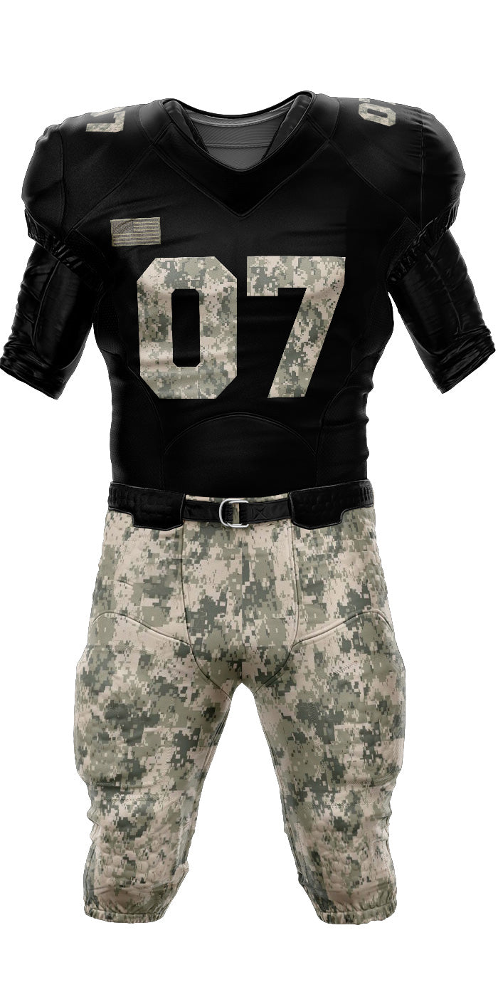 A full-length product image of an American football uniform set against a plain white background. The jersey is black with short sleeves, a subtle V-neck collar, and features the large number "07" printed on the front in a desert digital camouflage pattern. A muted gray American flag patch sits on the right chest area. The accompanying football pants are completely covered in the matching desert digital camouflage print, complete with integrated padding shapes and a black belt secured at the waist.
