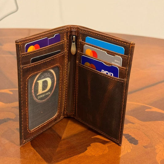 An open brown leather bifold wallet standing on a wooden table, showing card slots, a zipper, and a circular ID window with a logo.